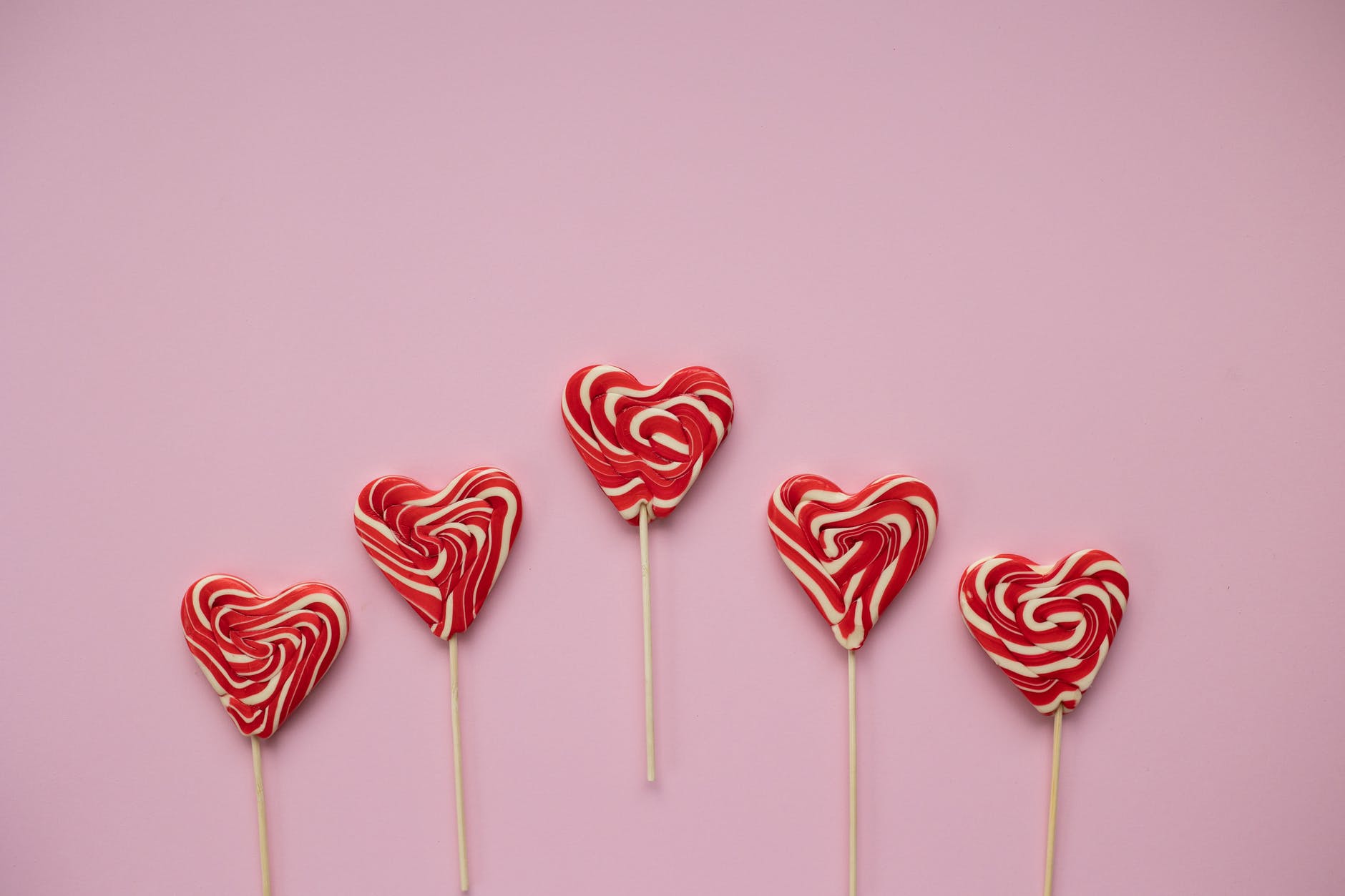 tasty lollipops in form of hearts placed on pink background